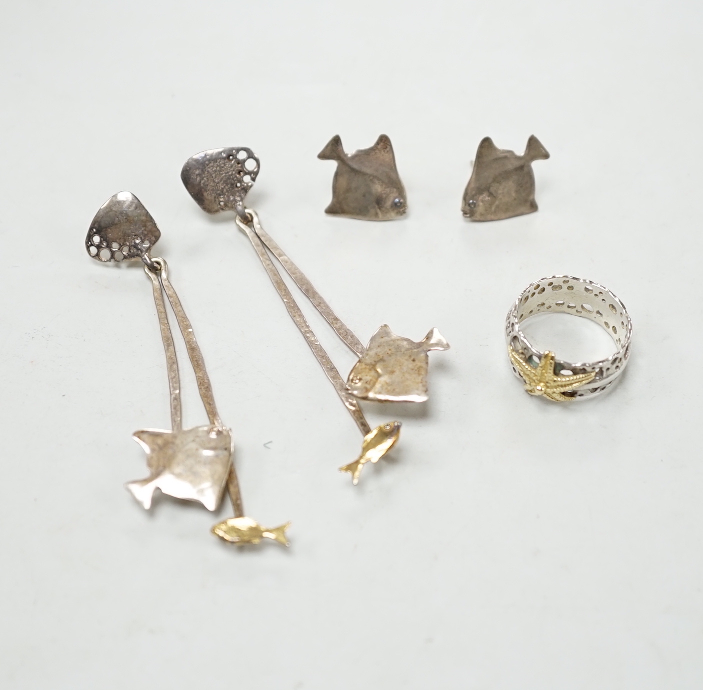 A modern Alan Vallis parcel gilt silver ring, with starfish motif, size O and two pairs of Alan Vallis silver earrings, both modelled with fish, longest overall 74mm.
